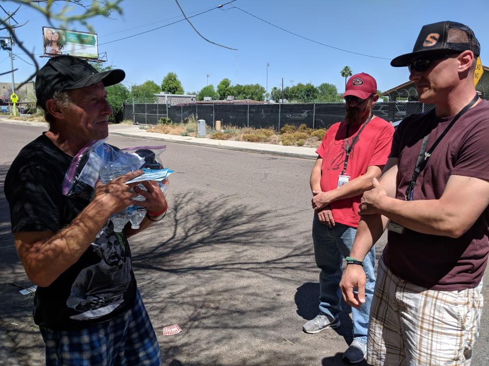 William Thompson (left) receives water and toiletries from Phoenix Rescue Mission. Thompson has been homeless on- and off-again for the past several years. During the summer, when people are most at risk for heat-related death, the Christian nonprofit distributes water and toiletries to homeless people in the Phoenix area. May 3, 2019. Priscilla Totiyapungprasert / The Republic.