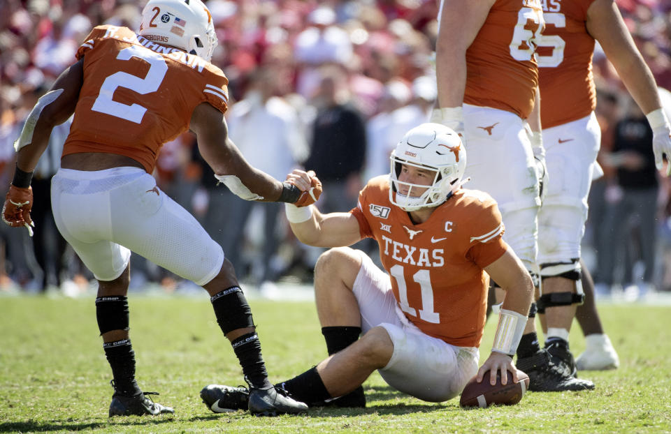 Texas quarterback Sam Ehlinger (11) is helped up by running back Roschon Johnson (2) after being sacked in the second half of an NCAA college football game against Oklahoma at the Cotton Bowl, Saturday, Oct. 12, 2019, in Dallas. Ehlinger was sacked 9 times as Oklahoma won 34-27. (AP Photo/Jeffrey McWhorter)