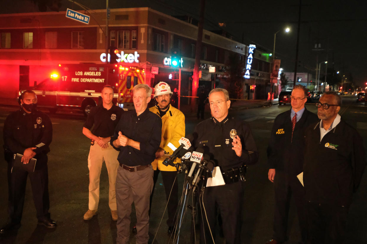 Michel Moore, center, chief of the Los Angeles Police Department, talks to the media after illegal fireworks seized at a South Los Angeles home exploded, in South Los Angeles Wednesday evening, June 30, 2021. A cache of the illegal fireworks exploded, damaging nearby homes and cars and causing injuries, authorities said. (AP Photo/Ringo H.W. Chiu)