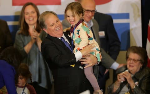 Doug Jones holds his granddaughter as he celebrates with supporters at the election night party in Birmingham - Credit:  REUTERS