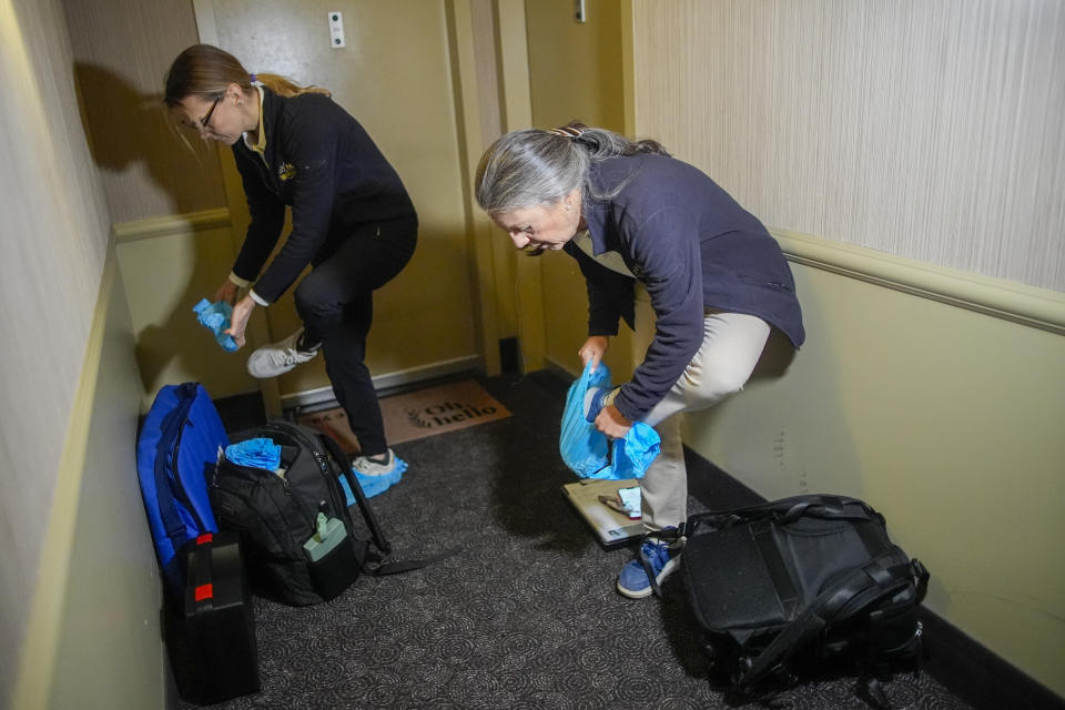 Dr. Amy Attas, right, and licensed veterinary technician Jeanine Lunz place cloth booties over their shoes before entering a clients apartment during a house call, Tuesday, April 23, 2024, in New York. (AP Photo/Mary Altaffer)