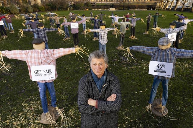 Riverford founder Guy Singh-Watson in front of 49 scarecrows outside Parliament