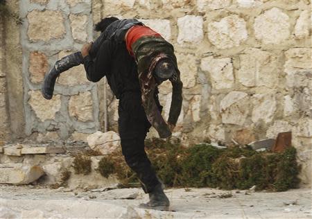 A Free Syrian Army fighter carries a body of a fellow fighter who was killed during what the FSA said was during clashes with forces loyal to Syria's President Bashar al-Assad near Base 80 near Aleppo International airport, November 8, 2013. REUTERS/Molhem Barakat