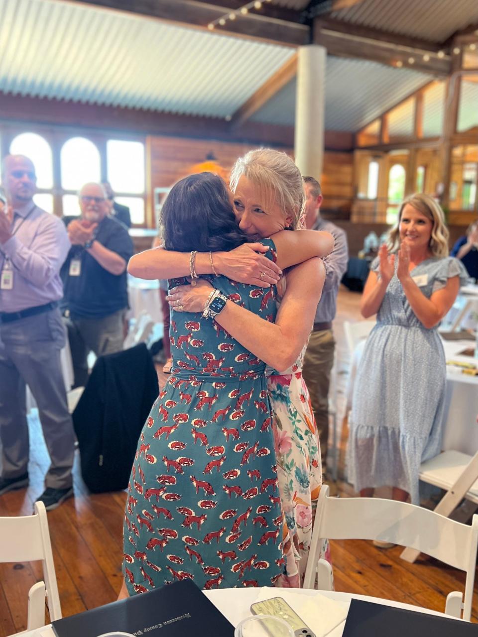 Karen Whiting gets a congratulatory hug after being named the Henderson County Public Schools' Teacher of the Year on Thursday at Jeter Mountain Farm.