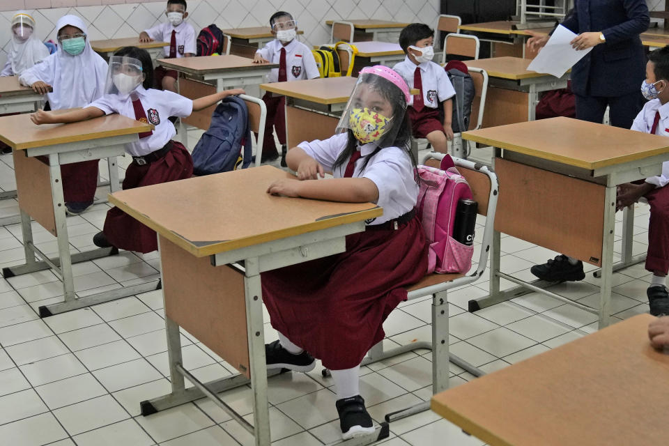 Students wearing face masks to help prevent the spread of COVID-19 attend class during the first day of school reopening at an elementary school in Jakarta, Indonesia, Monday, Aug. 30, 2021. Authorities in Indonesia's capital kicked off the school reopening after over a year of remote learning on Monday as the daily count of new COVID-19 cases in the country continues to decline. (AP Photo/Dita Alangkara)