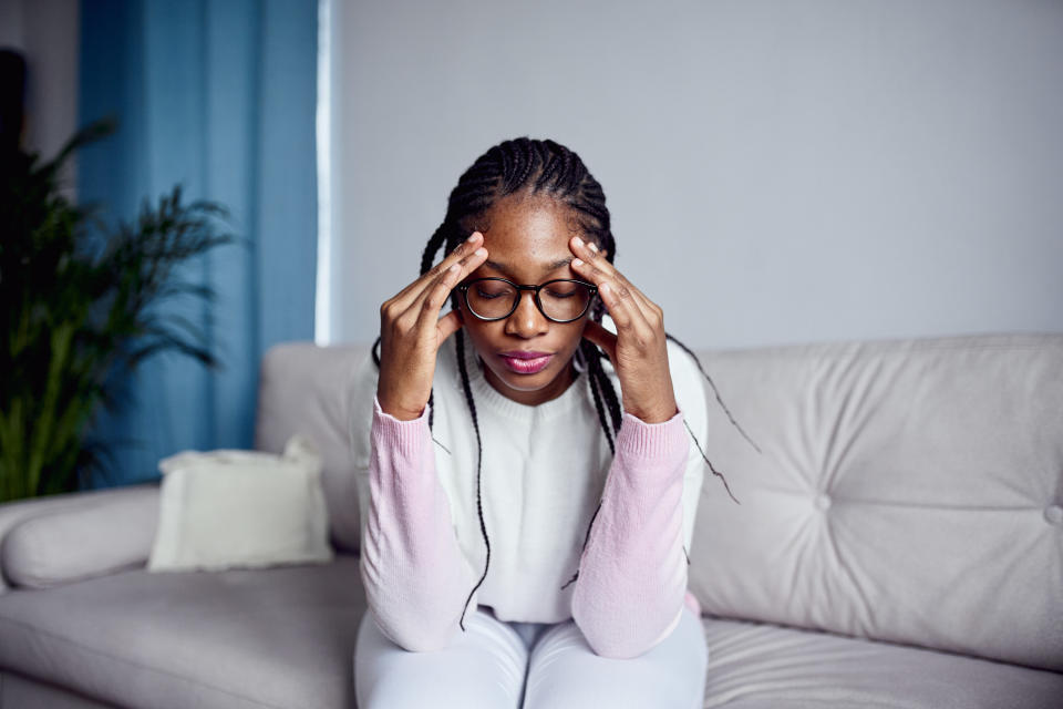 a woman sitting on the couch with hands to her head