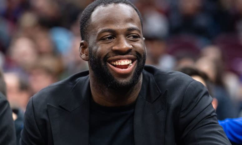 A closeup of a smiling Draymond Green sitting on the bench.