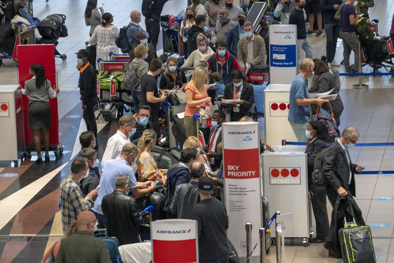 Decenas de personas hacen fila para tomar un vuelo de Air France a París en el aeropuerto internacional Tambo en Johannesburgo, Sudáfrica, el viernes 26 de noviembre de 2021.