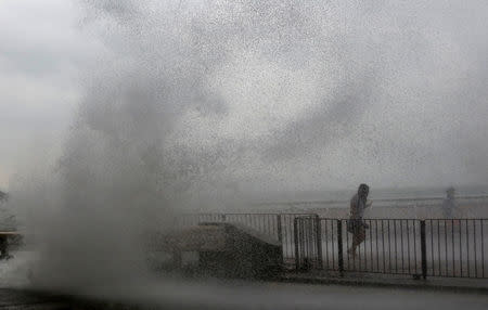 People run away from a big wave on a waterfront as Typhoon Haima approaches in Hong Kong, China, October 21, 2016 . REUTERS/Bobby Yip