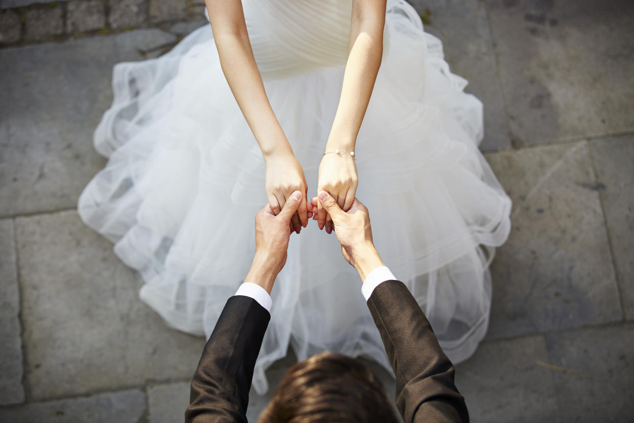 young asian newlywed couple wearing wedding dress dancing in open ground, high angle view.