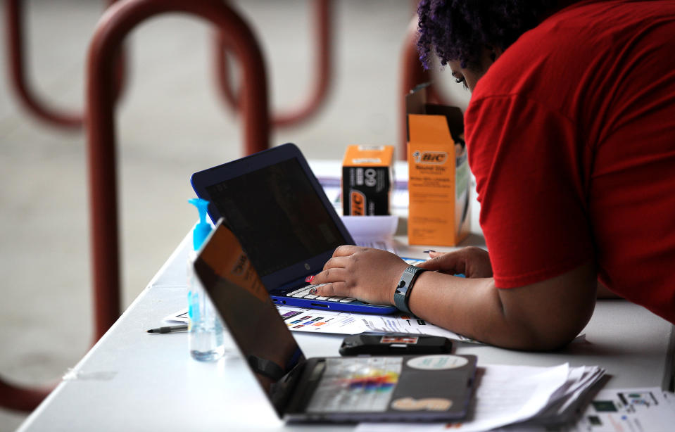 Image: A volunteer at a school handing out supplies including food, books and computers to students (Chris Graythen / Getty Images)