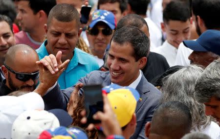 Venezuelan opposition leader Juan Guaido, who many nations have recognized as the country's rightful interim ruler, greets people during a swearing-in ceremony for supporters in Caracas, Venezuela April 27, 2019. REUTERS/Carlos Garcia Rawlins