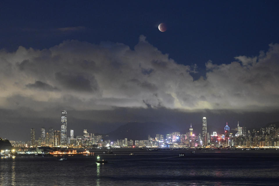 The moon rises over the Victoria Harbour in Hong Kong, Wednesday, May 26, 2021. The first total lunar eclipse in more than two years coincides with a supermoon this week for quite a cosmic show. (AP Photo/Kin Cheung)