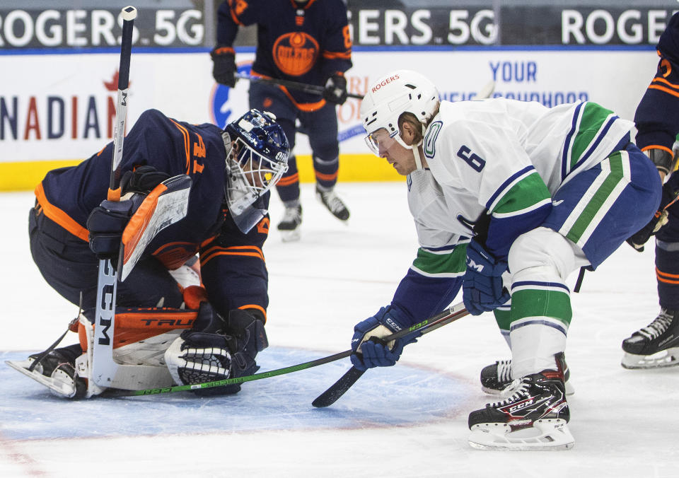 Edmonton Oilers goalie Mike Smith (41) makes a save on Vancouver Canucks' Brock Boeser (6) during the first period of an NHL hockey game Saturday, May 8, 2021, in Edmonton, Alberta. (Jason Franson/The Canadian Press via AP)