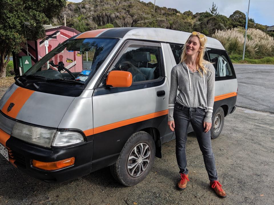 The writer standing in front of a gray and orange van