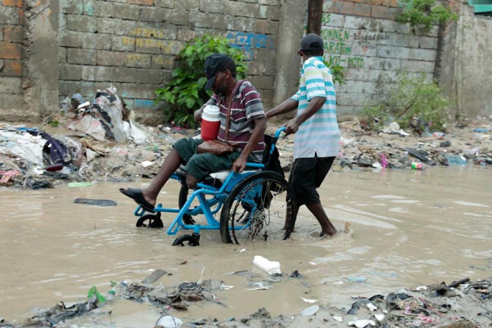 Un hombre en silla de ruedas recibe ayuda para atravesar una calle inundada tras una fuerte lluvia, en Puerto Príncipe, Haití, el 3 de junio de 2023.