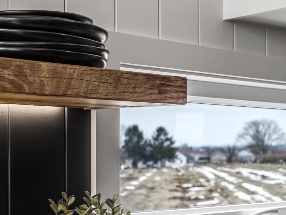 kitchen shelves next to a window showing a snowy field