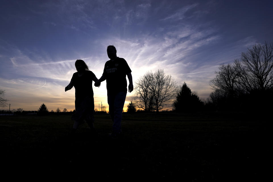 Keri Wegg, left, and her husband, Rodney, return to their Westfield, Ind., home after a short walk in the setting sun on Sunday, March 21, 2021. They met in 2004 at a round-the-clock Mexican restaurant favored by hospital workers getting off nightshifts. (AP Photo/Charles Rex Arbogast)