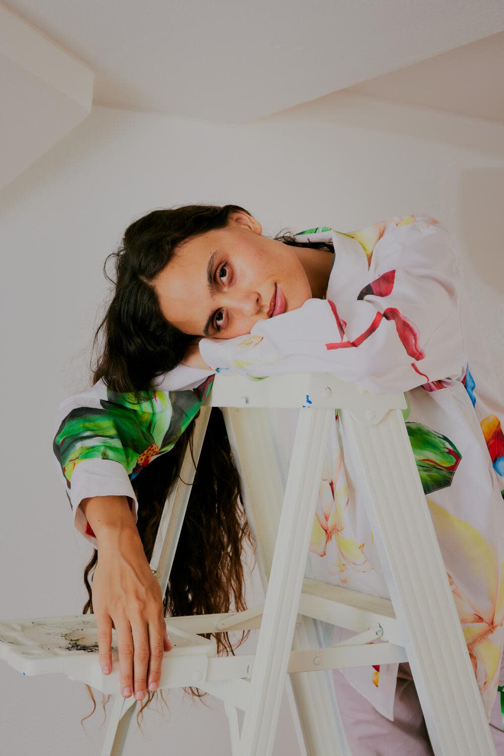 A photo of a woman leaning over a ladder, her long hair hanging down the side.