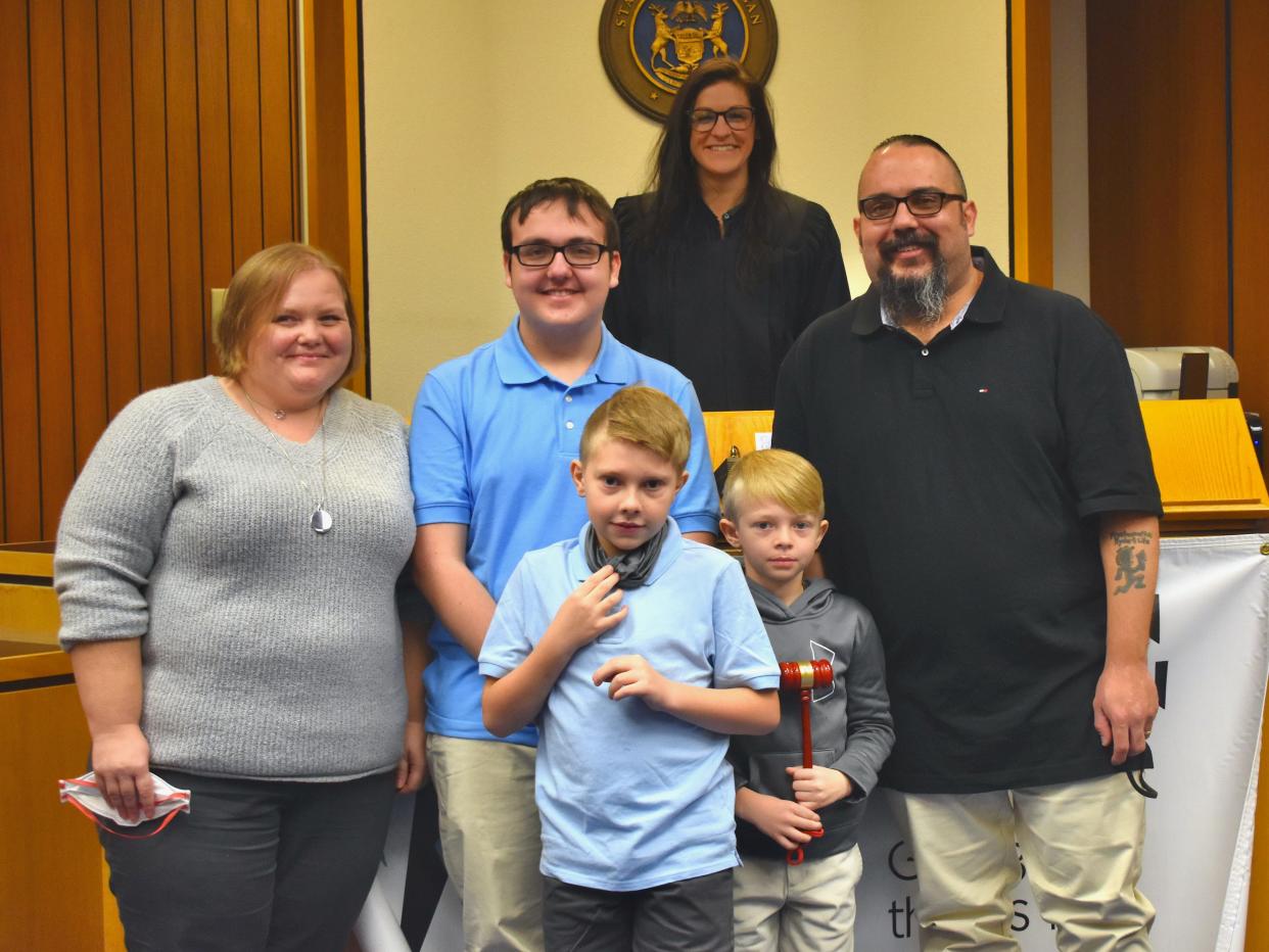 Lenawee County observed Adoption Day Monday. Probate Judge Catherine A. Sala, pictured in the back, granted approval of Brigitte, left, and Dennis Sneyd, right, adopting Brantly, 10, and Seth, 8, holding gavel. Also pictured is Joseph Sneyd, the son of Brigitte and Dennis.
