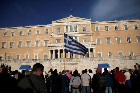 A protester waves a Greek flag during a demonstration outside the parliament building in central Athens, Greece where lawmakers were discussing controversial tax and pension reforms May 8, 2016. REUTERS/Alkis Konstantinidis