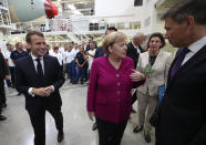 French President Emmanuel Macron and German Chancellor Angela Merkel visit the assembly line of the Airbus A350 in Toulouse, southwestern France, Wednesday, Oct.16, 2019. French President Emmanuel Macron and German Chancellor Angela Merkel are meeting in southern France, one day before a key EU summit that may approve a divorce deal with Britain. (AP Photo/Frederic Scheiber, Pool)