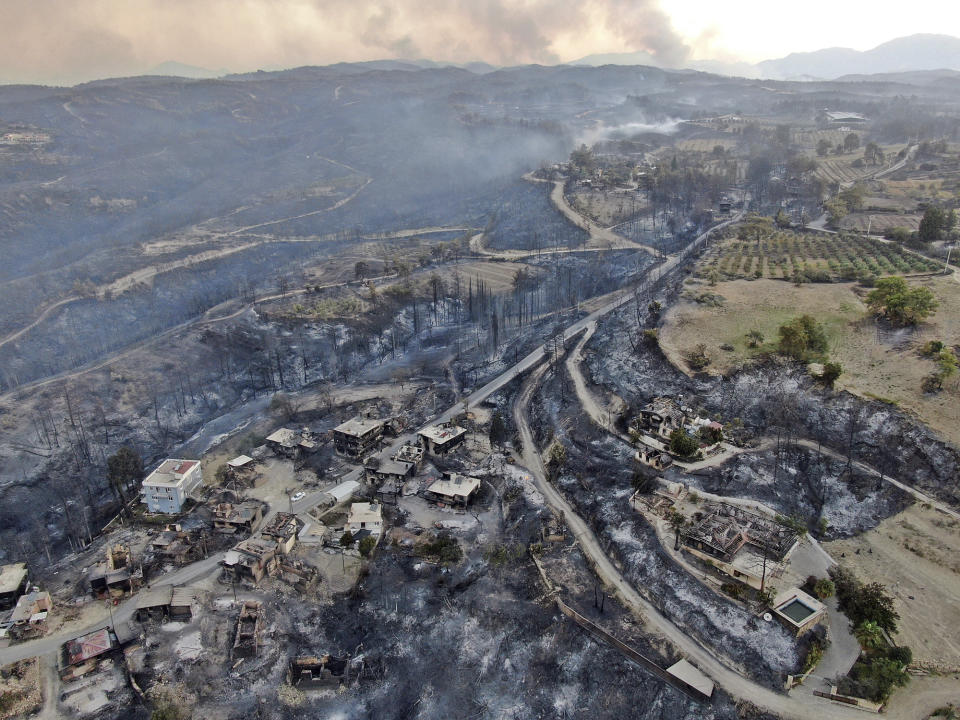 An aerial photo shows destroyed houses in a village as wildfires continue to rage the forests near the Mediterranean coastal town of Manavgat, Antalya, Turkey, Thursday, July 29, 2021. Authorities evacuated homes in southern Turkey as a wildfire fanned by strong winds raged through a forest area near the Mediterranean coastal town of Manavgat. District governor Mustafa Yigit said residents of four neighborhoods were moved out of the fire's path as firefighters worked to control the blaze that broke out Wednesday. It was not immediately clear what caused the fire but authorities said nearby tourist resorts were not affected. (Suat Metin/IHA via AP)