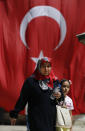 People walk past a Turkish flag on a mosque compound in Istanbul, Wednesday, Aug. 15, 2018. The Turkish lira currency has nosedived in value in the past week over concerns about Turkey's President Recep Tayyip Erdogan's economic policies and after the United States slapped sanctions on Turkey angered by the continued detention of an American pastor. (AP Photo/Lefteris Pitarakis)