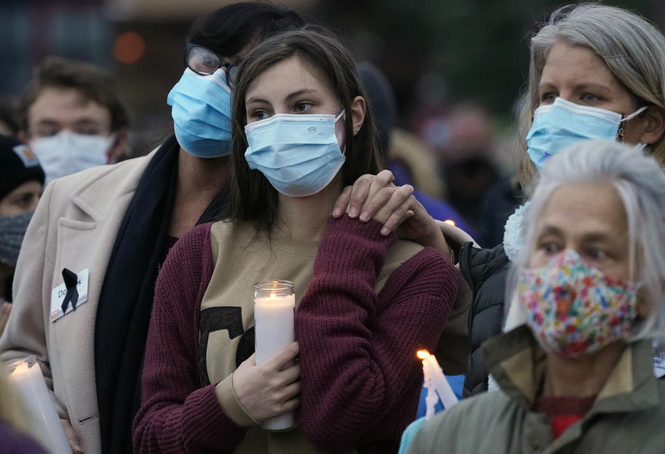 Mourners console each other at a vigil for the 10 victims of the Monday massacre at a King Soopers grocery store late Thursday, March 25, 2021, at Fairview High School in Boulder, Colo. (AP Photo/David Zalubowski)