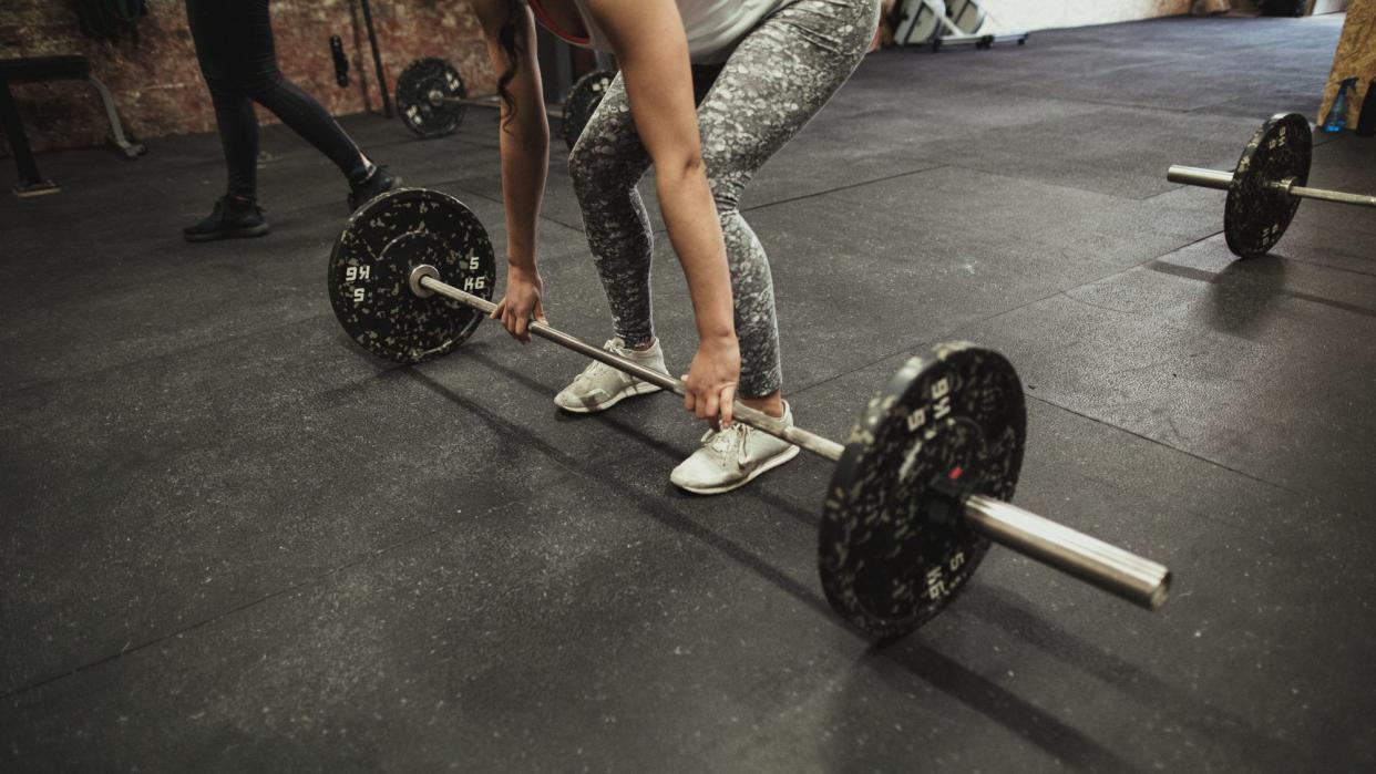 guide to deadlifts: Woman Performing a barbell Deadlift working leg, butt, and back muscles