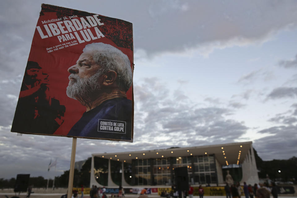 A supporter of Luiz Inacio Lula da Silva carries a poster that says in Portuguese "Freedom for Lula" as his lawyers ask the Supreme Court, behind, to free him after he was jailed in connection with the "Car Wash" corruption investigation in Brasilia, Brazil, Tuesday, June 25, 2019. Da Silva’s lawyers argue then-judge Sergio Moro offered guidance to prosecutors in investigations that led to da Silva’s conviction. Moro has said he did nothing improper. The court denied the petition. (AP Photo/Eraldo Peres)