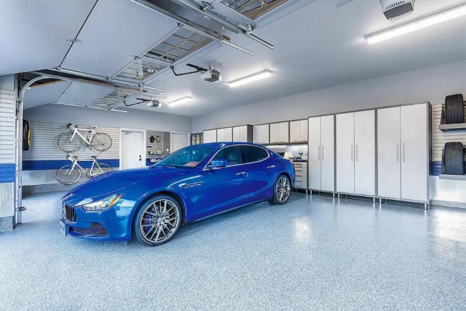 A blue car is parked in a garaged with a sealed floor.