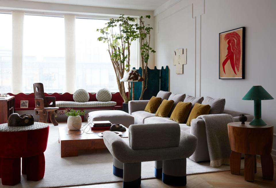 Valle’s Smile chair (foreground) was inspired in part by the Ethiopian chief chair near the windows; Schumacher window panel fabric. An artwork by Jayson Musson hangs above the custom sofa, with its Holland & Sherry fabric, and a vintage coffee table by Milo Baughman; wool rug from Stark. A Ron Rezek lamp sits on the 1950s French butcher-block side table. Valle designed the folding screen and the window seat; its cushions are covered in the same Le Manach fabric that is used on the top of Valle’s velvet side table.