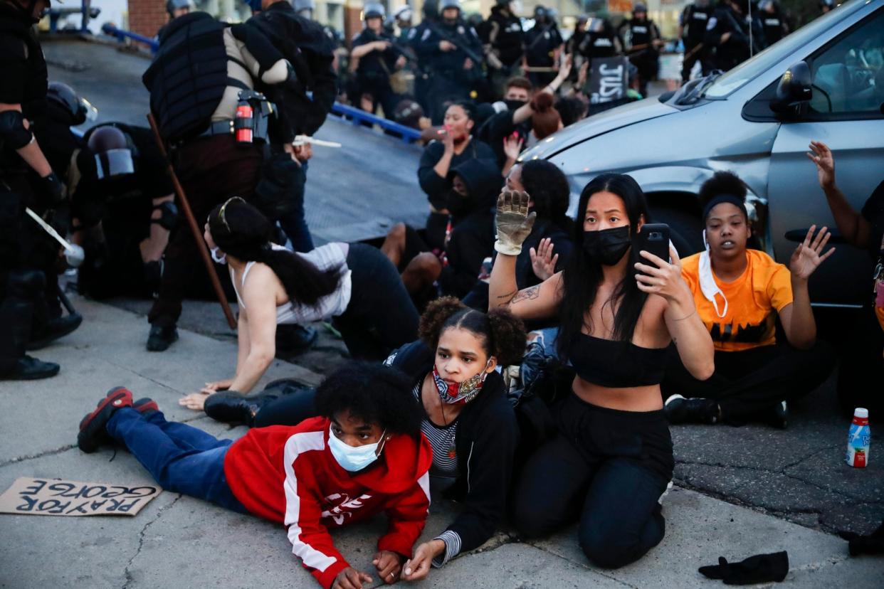 Protesters raise their hands on command from police as they are detained prior to arrest and processing at a gas station on South Washington Street in Minneapolis: AP
