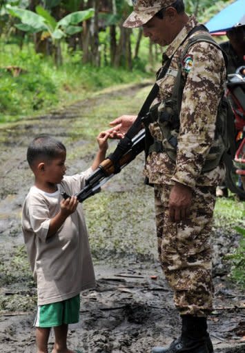 A young boy is seen touching the rifle of a Moro Islamic Liberation Front (MILF) rebel inside the group's base at Camp Darapan, Sultan Kudarat province, on the southern Philippine island of Mindanao, in 2011. MILF rebels waging a decades-long insurgency in which more than 150,000 people have died are aiming to sign a roadmap for peace this year, according to their chief negotiator