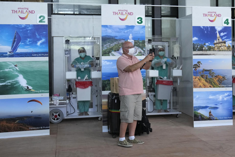 A tourist take a picture after a COVID-19 swab test after arriving at the Phuket International Airport in Phuket, southern Thailand,Thursday, July 1, 2021. Starting Thursday, Thailand will welcome back international visitors — as long as they are vaccinated — to its famous southern resort island of Phuket without having to be cooped up in a hotel room for a 14-day quarantine. (AP Photo/Sakchai Lalit)