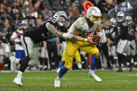 Los Angeles Chargers quarterback Justin Herbert (10) scrambles away from Las Vegas Raiders defensive end Maxx Crosby (98) during the second half of an NFL football game, Sunday, Dec. 4, 2022, in Las Vegas. (AP Photo/David Becker)