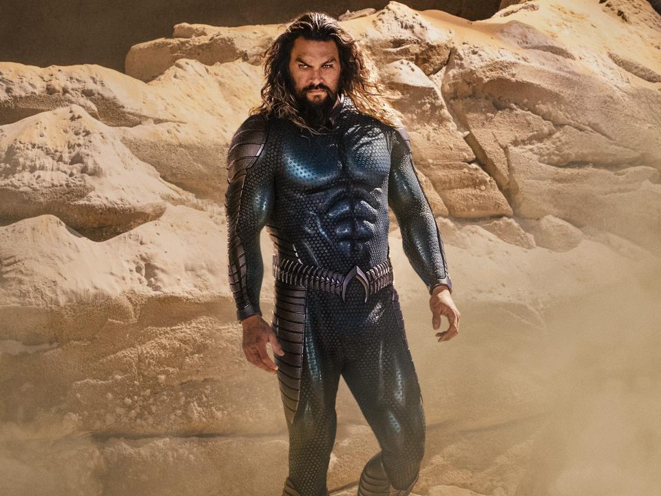 Jason Momoa standing in a blue superhero suit as Aquaman in "Aquaman and the Lost Kingdom."