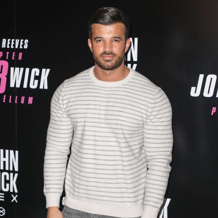 Mike in striped sweater and distressed jeans posing at a John Wick film event