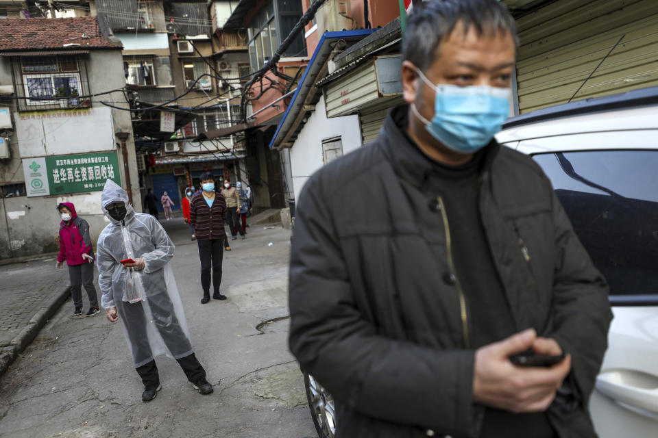 In this March 18, 2020, photo, people stand in a spaced line as they wait to buy pork at the entrance gate of a closed residential community in Wuhan in central China's Hubei Province. Last month, Wuhan was overwhelmed with thousands of new cases of coronavirus each day. But in a dramatic development that underscores just how much the outbreak has pivoted toward Europe and the United States, Chinese authorities said Thursday that the city and its surrounding province had no new cases to report. The virus causes only mild or moderate symptoms, such as fever and cough, for most people, but severe illness is more likely in the elderly and people with existing health problems. (Chinatopix via AP)