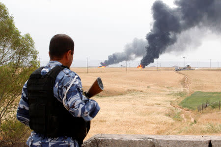 A member of the Kurdish security forces stands guard after explosions at two oil wells in Khabbaz oilfield, 20 km (12 miles) southwest of Kirkuk in Iraq, May 4, 2016. REUTERS/Ako Rasheed