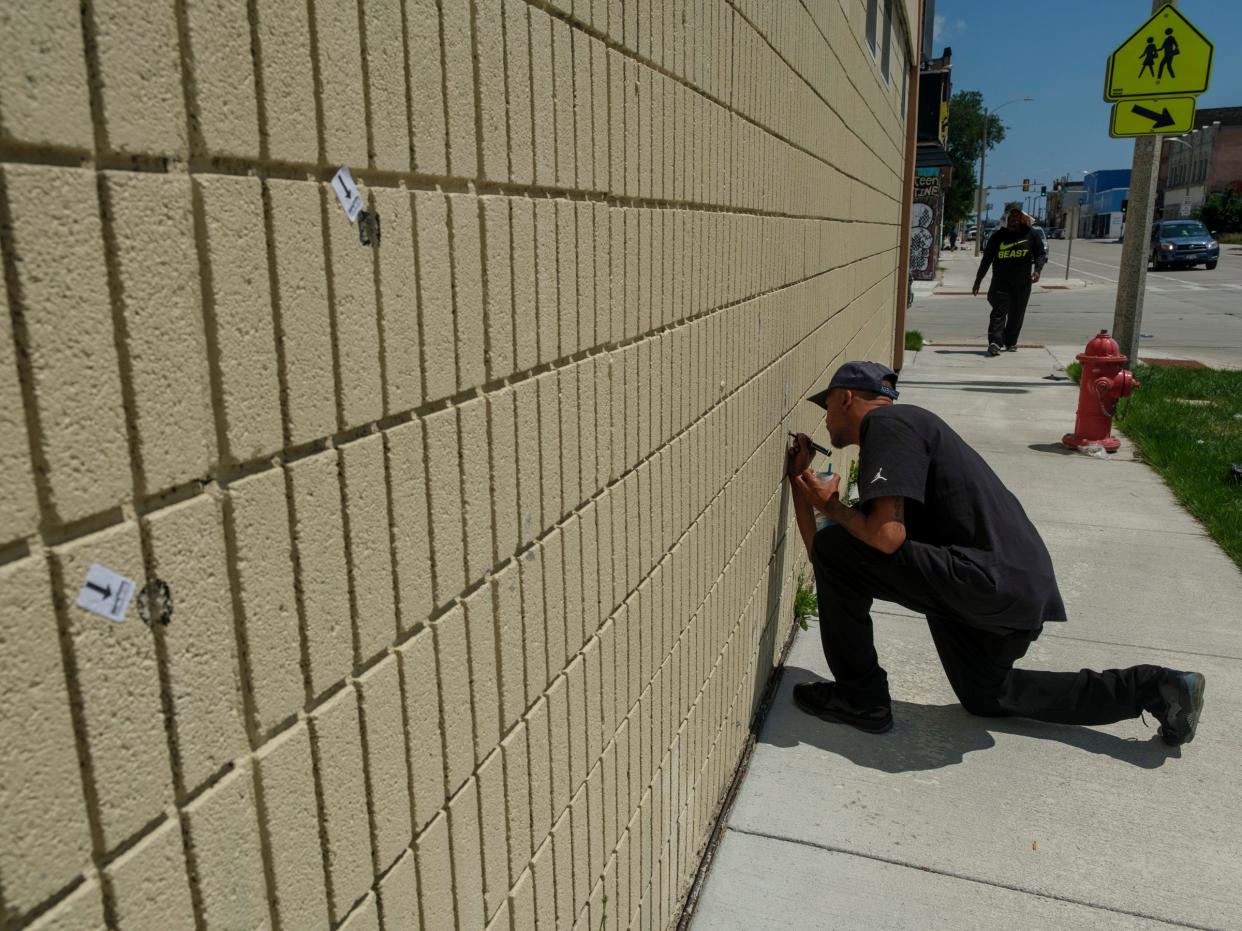 A man highlights bullet holes in a wall along Vliet Street after a man identified as Samuel Sharpe Jr. was fatally shot by Columbus police officers in Milwaukee, Wisconsin on Wednesday, July 17, 2024. - Max Correa / Milwaukee Journal Sentinel