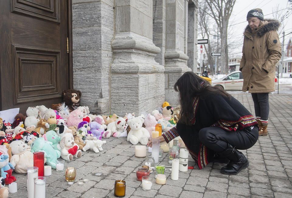 A woman lights a candle at a memorial outside a church close to the site of a daycare centre in Laval, Quebec, Thursday, Feb. 9, 2023, where a bus crashed into the building killing two children. (Graham Hughes/The Canadian Press via AP)