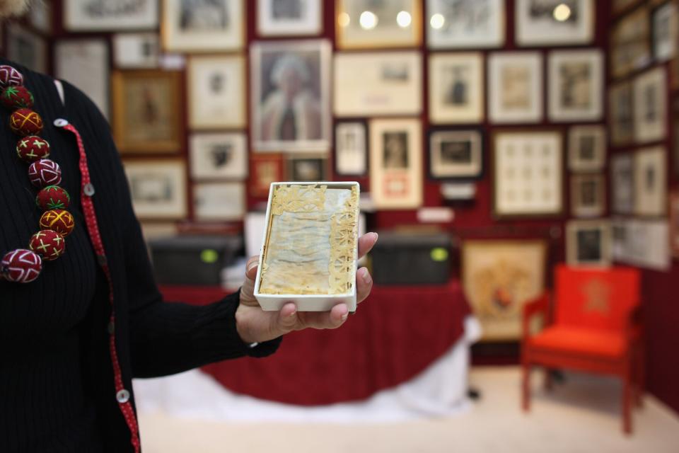 A woman holds a piece of wedding cake from the wedding of Prince Charles and Princess Diana in 1981 at the Olympia International Fine Art and Antiques Fair