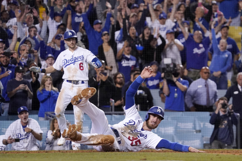 Los Angeles Dodgers' Cody Bellinger, below, scores the winning run on a single by Mookie Betts as Trea Turner watches during the ninth inning of a baseball game against the Colorado Rockies Wednesday, July 6, 2022, in Los Angeles. (AP Photo/Mark J. Terrill)