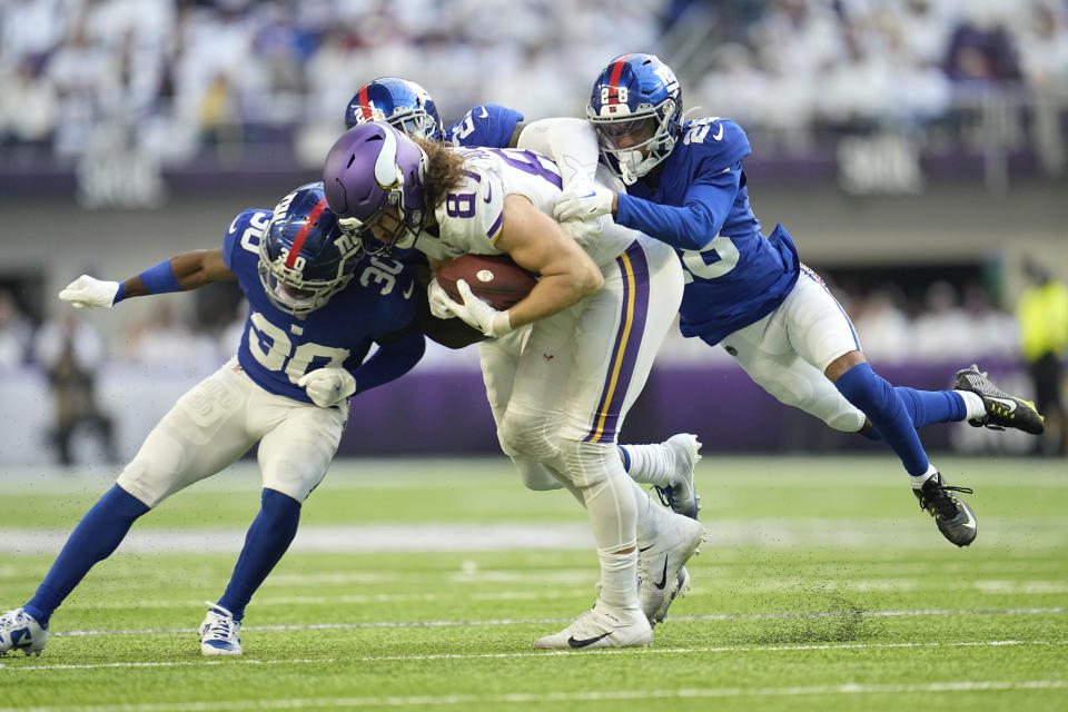 Minnesota Vikings tight end T.J. Hockenson (87) catches a pass between New York Giants cornerback Darnay Holmes (30) and cornerback Cor'Dale Flott (28) during the first half of an NFL football game, Saturday, Dec. 24, 2022, in Minneapolis. (AP Photo/Abbie Parr)