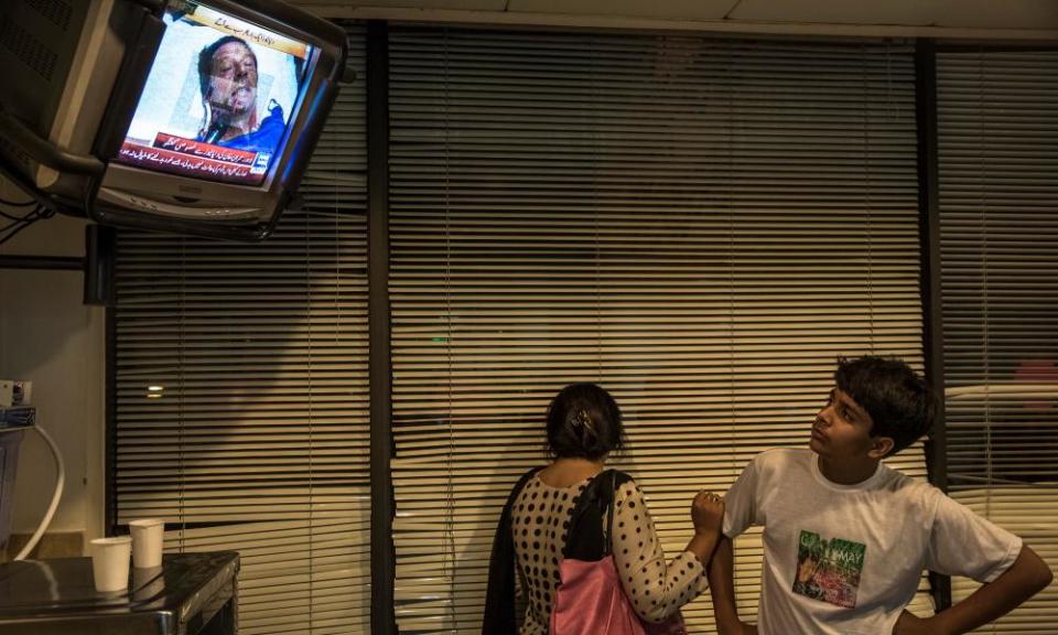 People watch a 2013 television interview with Imran Khan in intensive care after he sustained an injury falling.