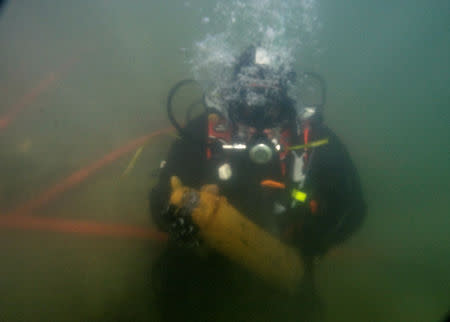 A diver from a bomb-disposal unit holds underwater an unexploded shell recovered in Meuse river at Sivry-sur-Meuse, close to WWI battlefields, near Verdun, France, October 23, 2018 before the centenial commemoration of the First World War Armistice Day. REUTERS/Pascal Rossignol