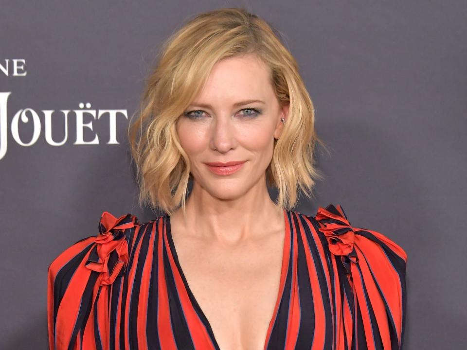 cate blanchett wearing a red and black striped dress in front of a gray background