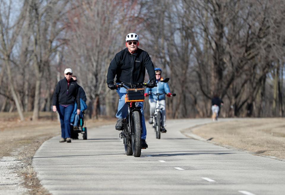 Bicyclists and walkers make use of the Fox River Trail during a sunny day with temperatures in the high 50s on March 8, 2021, in De Pere, Wis.